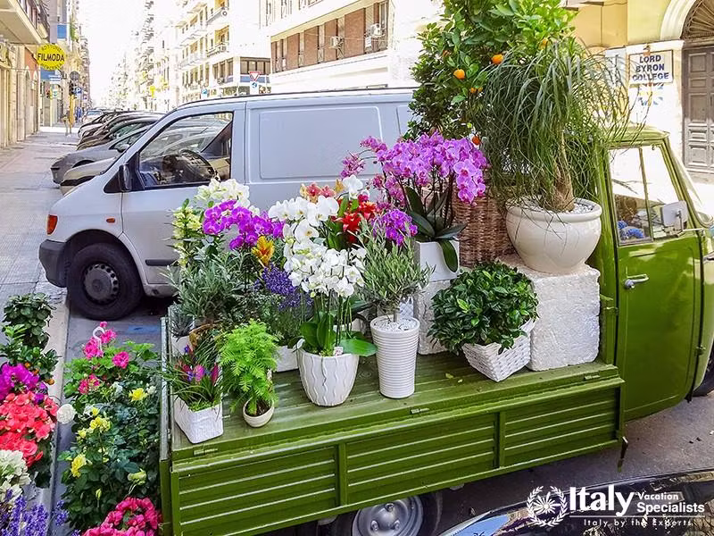 Vintage small cargo three-wheeled car, in the back of which flower pots with flowers for sale. Bari 