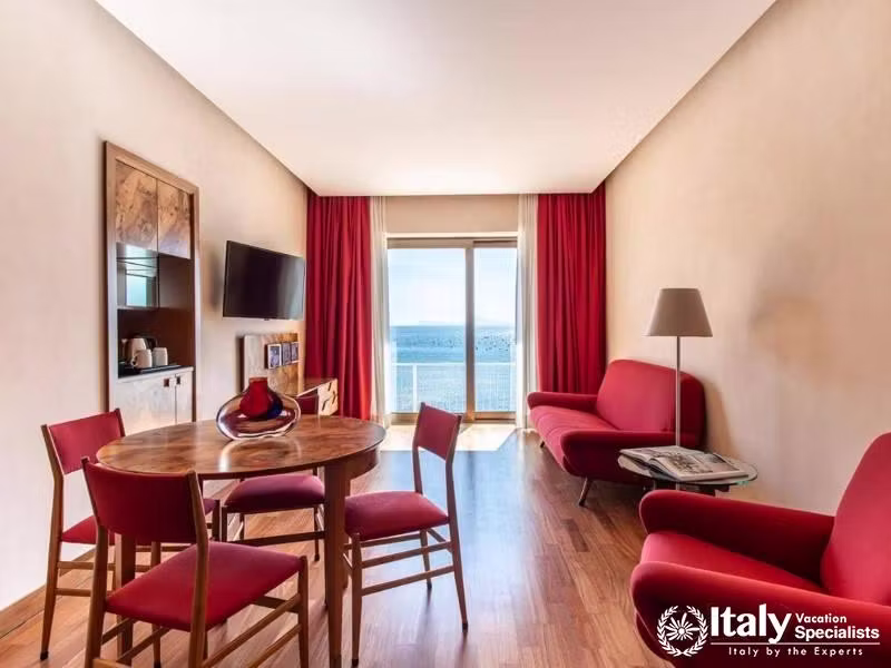 A cozy living room with red accents and a scenic balcony view.
