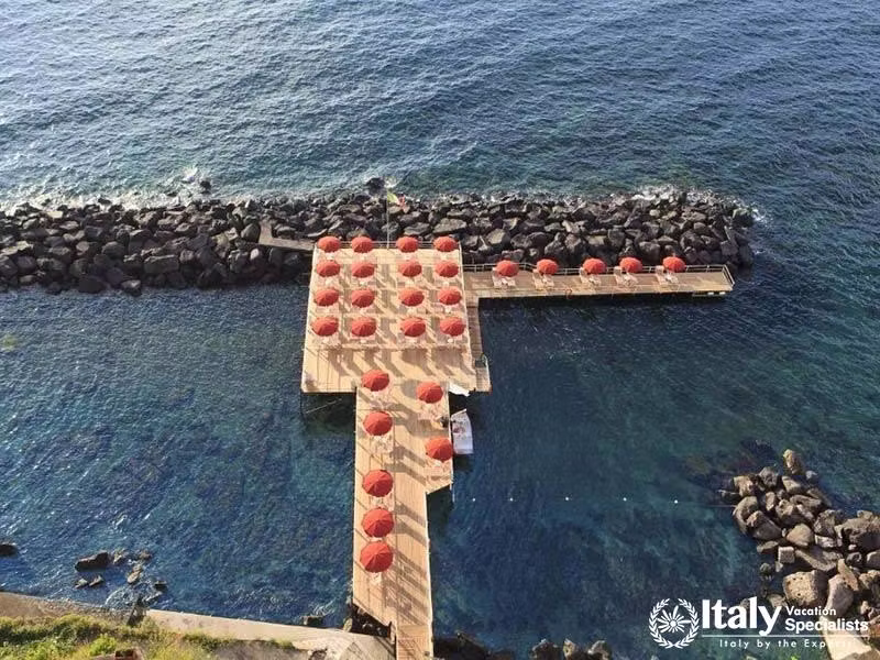 Private beach deck with red umbrellas on the stunning coast.