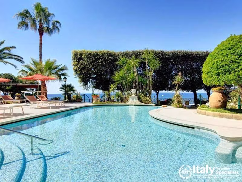 Sparkling outdoor pool surrounded by lush greenery and palms.