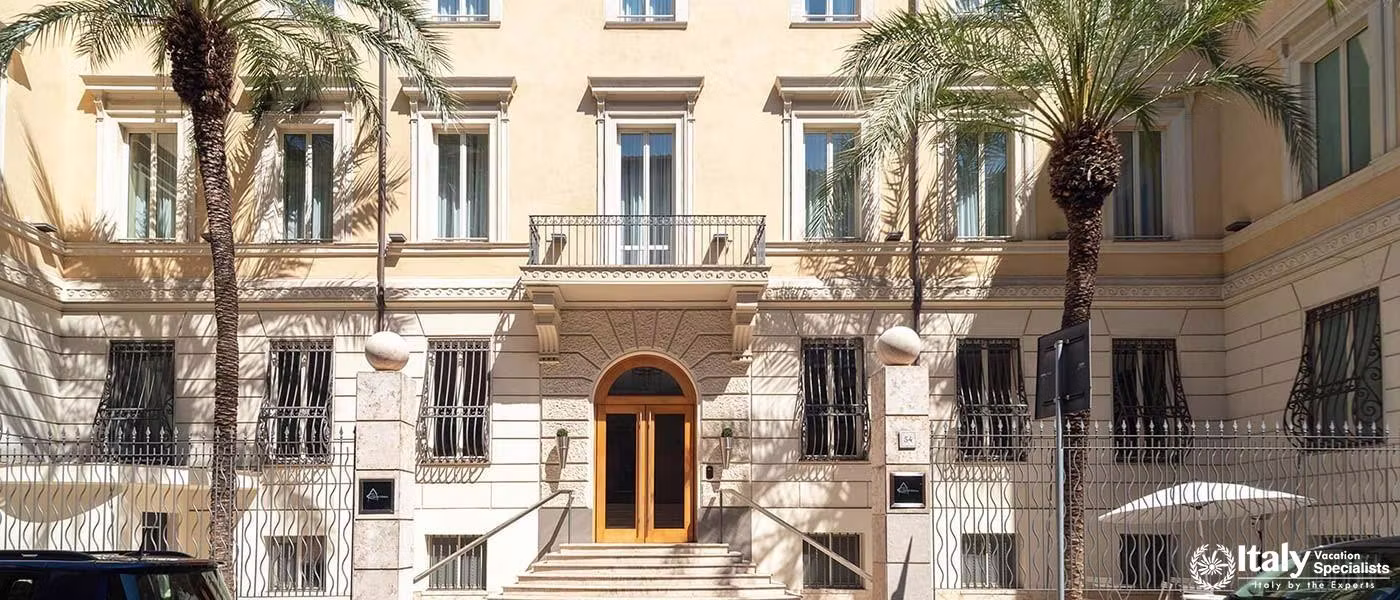The grand facade of the Hotel Capo d'Africa, framed by palm trees and showcasing its stately archite