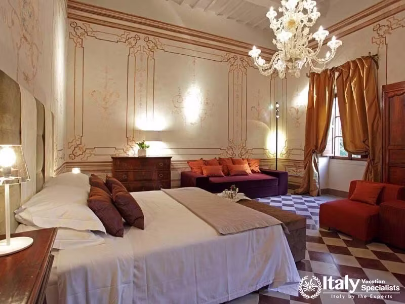 Elegant bedroom with ornate frescoes and a lavish chandelier, creating a regal atmosphere.