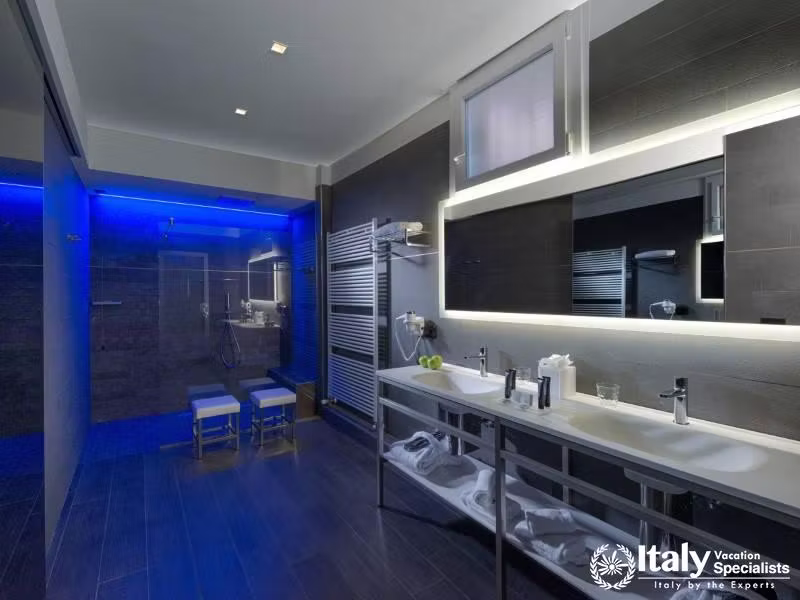 Indulge in luxury with our spacious, modern bathroom featuring sleek design and vibrant lighting.