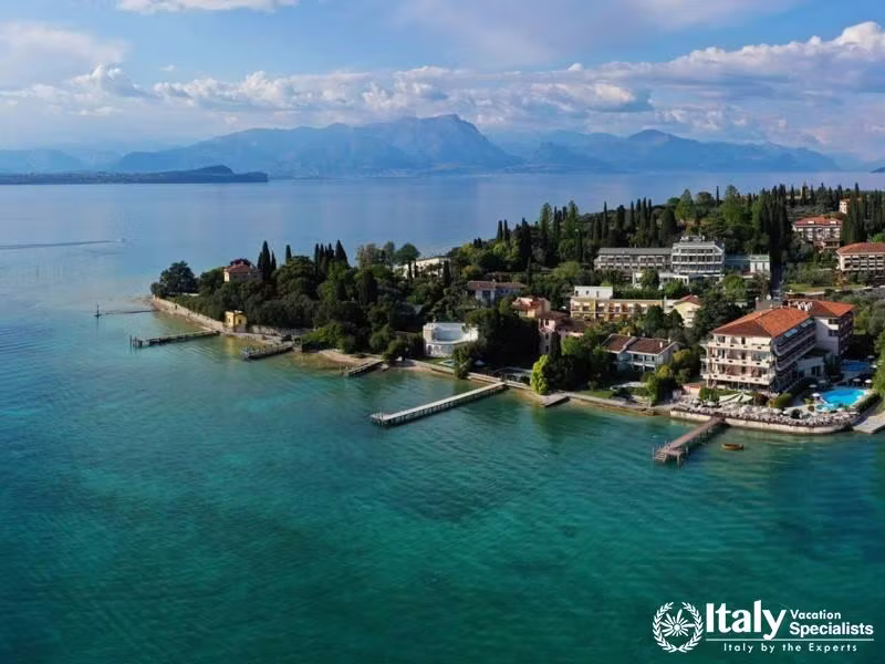 A scenic view of the hotel by the lakeside, surrounded by lush greenery and clear blue waters.