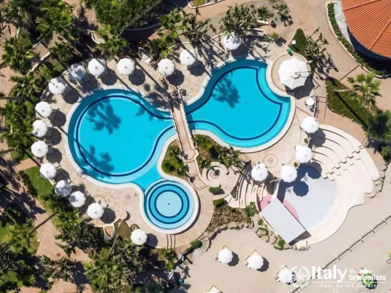 Villaggio Il Gabbianos pool, a blue oasis, is a birds-eye beauty amidst palm fronds.