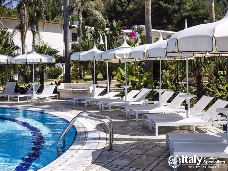 Poolside lounging at Villaggio Il Gabbiano offers sunny repose amid lush greenery.