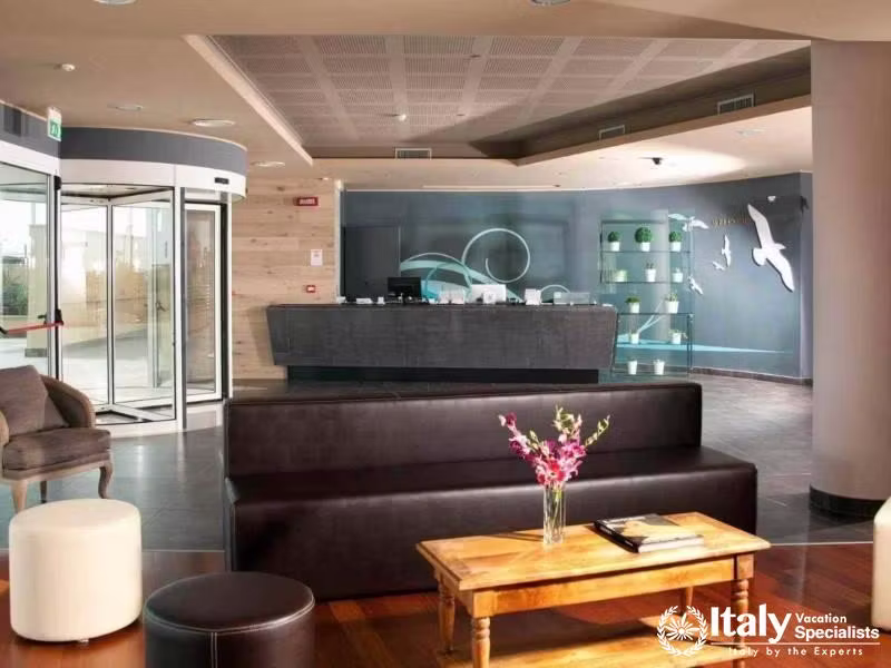 An elegant hotel lobby featuring a dark brown sofa, a stylish reception desk, and modern decor.