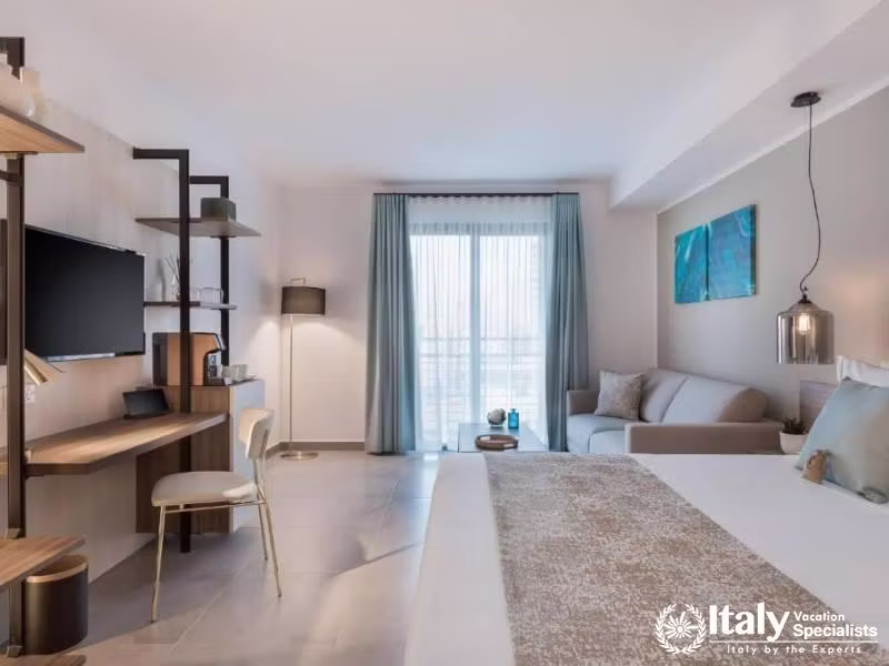 A modern hotel room with a comfortable bed, work desk, and balcony access.