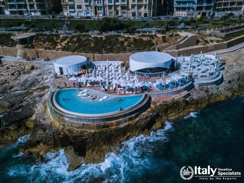 An outdoor pool area with a stunning view of the coastline, featuring luxurious loungers and a styli
