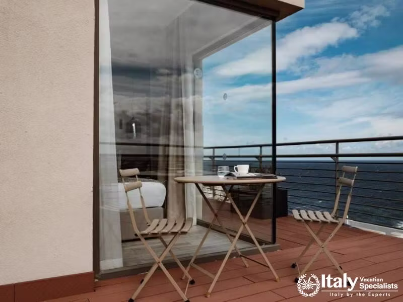 A charming balcony with a small table and chairs, offering a stunning view of the sea.