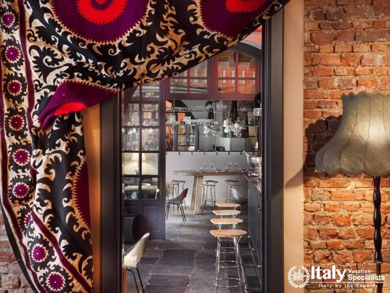 Stylish restaurant view at Hotel Maison Borella through rich textile curtains.