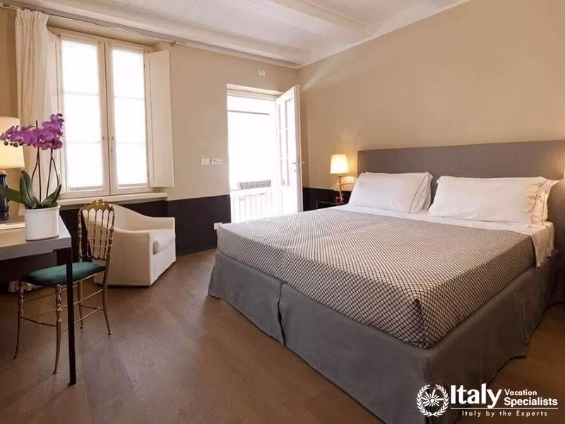 Bright double room at Hotel Maison Borella with balcony access.
