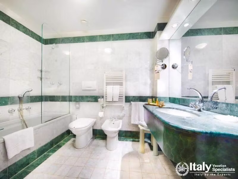 Marble and mosaic elegance in the spacious bathroom at Hotel Colombina.