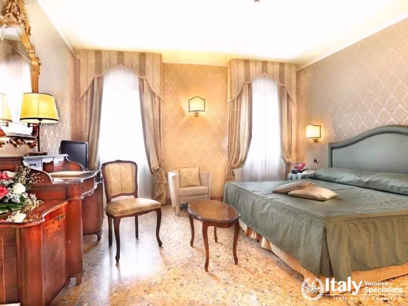 A serene sleep space with classic Venetian furniture at Hotel Colombina.
