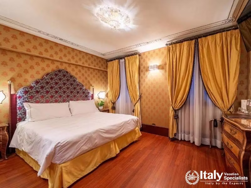A rich tapestry headboard and golden drapes evoke a sense of opulence in this room at Hotel Colombin