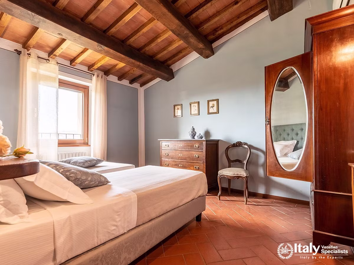 Bright Tuscan Bedroom with Exposed Wooden Beams at Villa Buccelletti