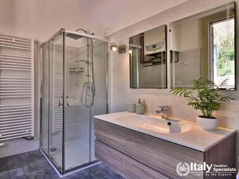 Modern Serenity: Sleek bathroom with glass shower and verdant views in Villa Lago Elegante
