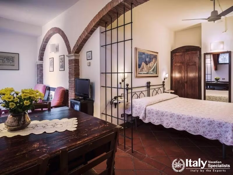 Spacious studio layout with separate sleeping, dining, and sitting areas beneath classic brick arche