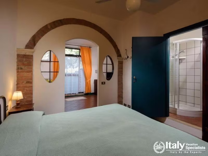 Bedroom with archway leading to a sunny patio and an adjoining bathroom.