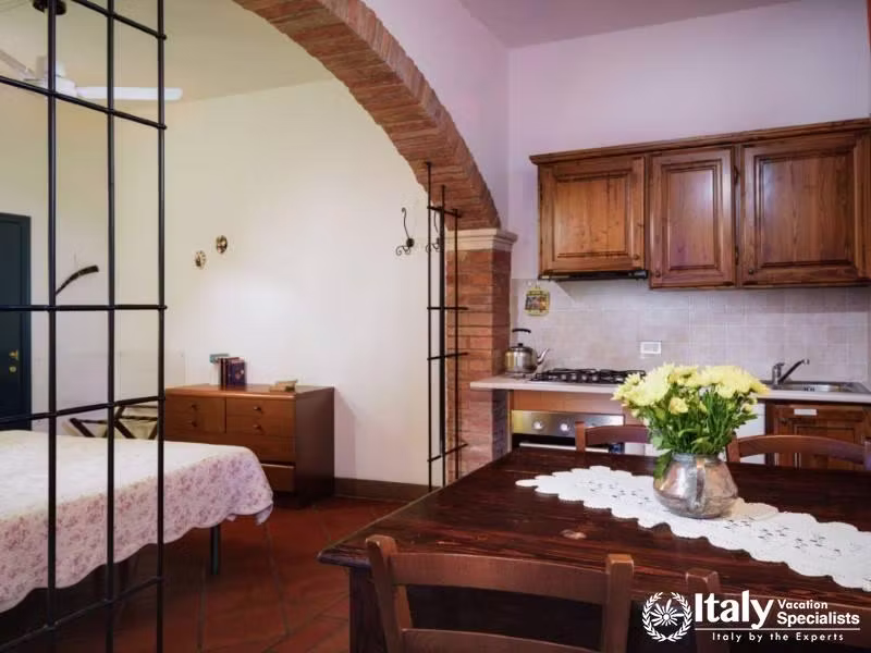 Combined living and dining area featuring a kitchenette and rustic brick archways.