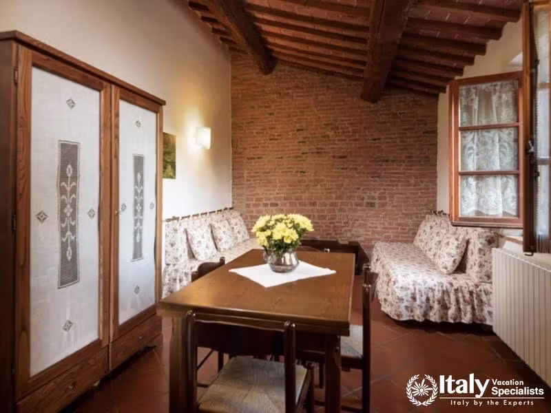 Cozy sitting room with exposed brick, wood beam ceilings, and floral upholstery.