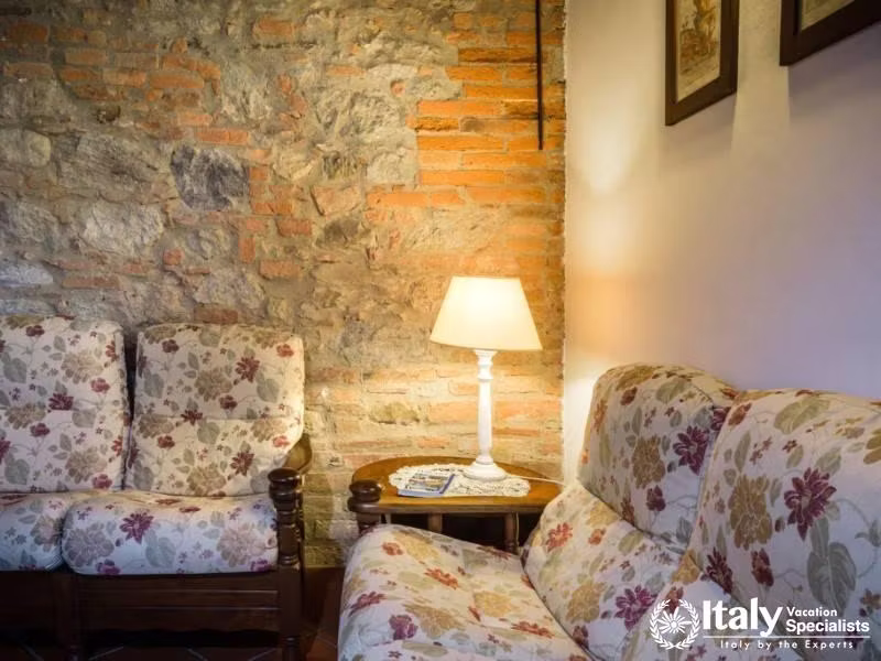 Inviting living area with floral couches and a vintage exposed brick backdrop.