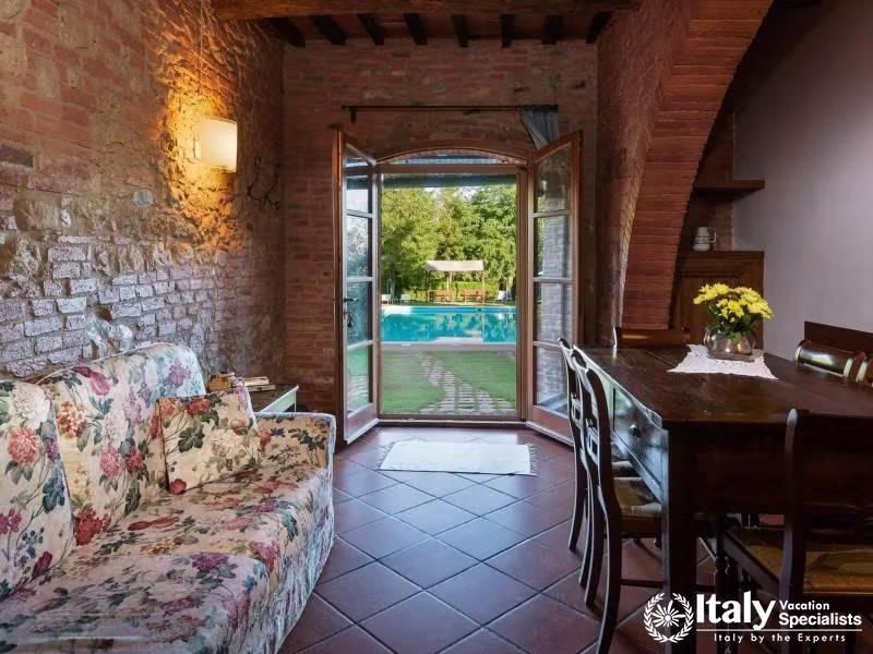 Lounge area with direct access to the pool, featuring a floral couch and rustic dining table.