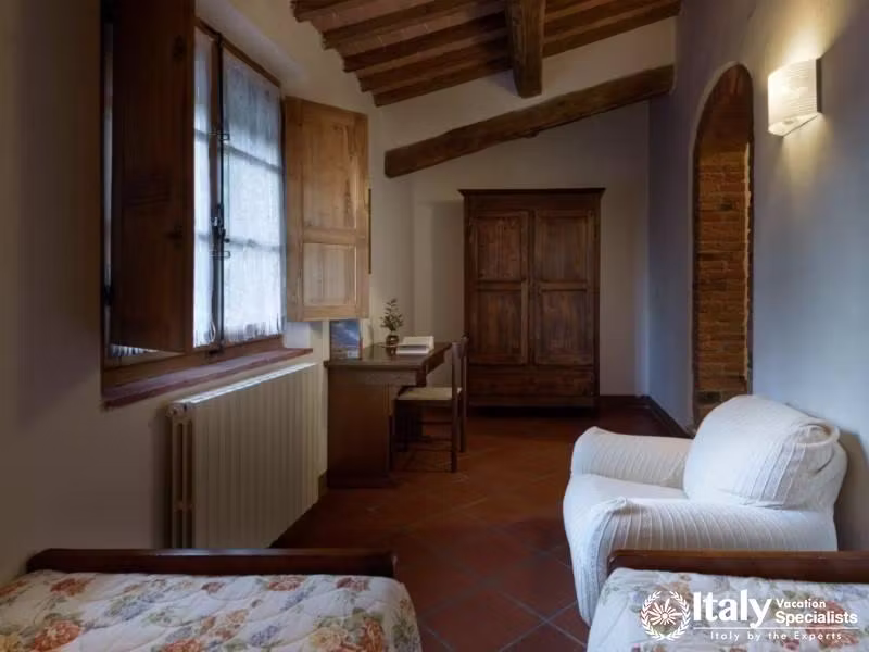 Spacious room featuring twin beds and a cozy reading nook with a large wooden wardrobe.
