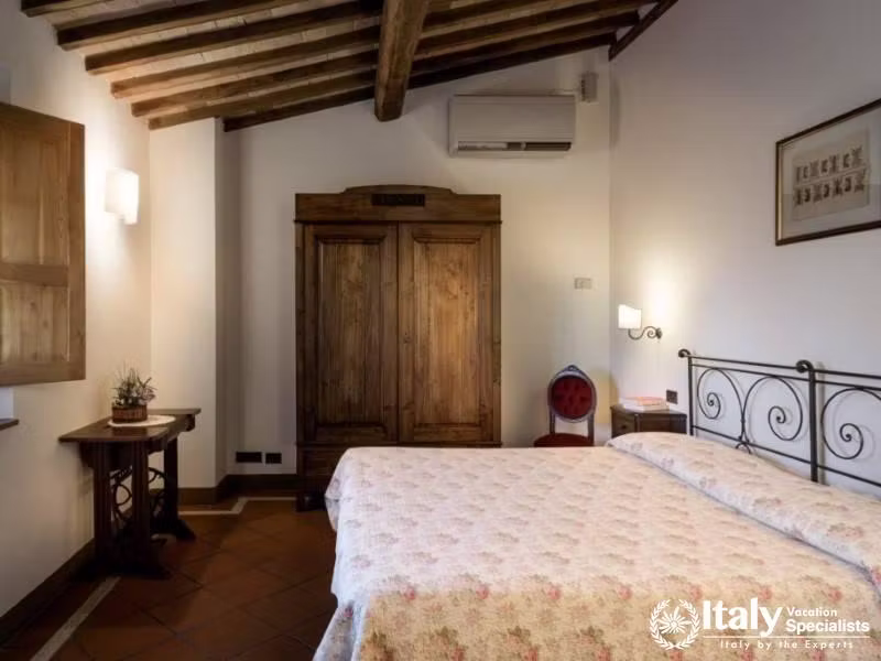 Features a vintage metal bed frame and wooden wardrobe, with a blend of modern and traditional decor