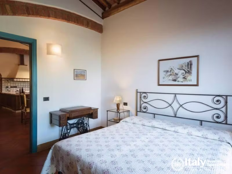 Inviting bedroom with a view into the kitchen, enhanced by traditional dÃ©cor and natural light.