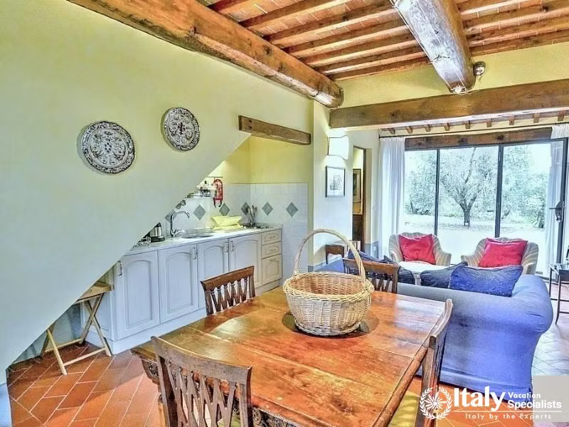 Rustic kitchen with wooden beams and outdoor view.