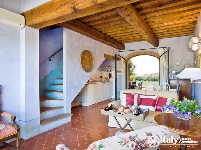 Cozy living room with wooden beams and a staircase.