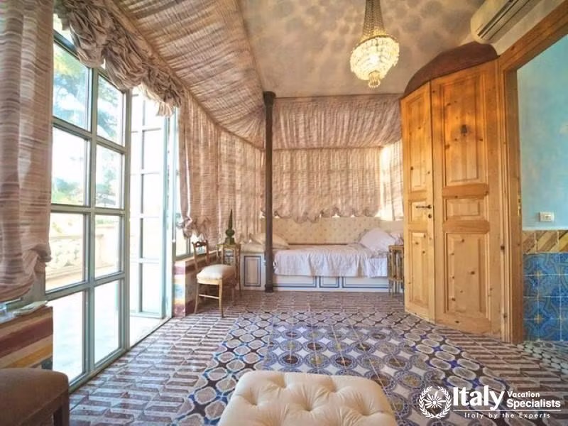 Spacious bedroom with patterned curtains and a chandelier.