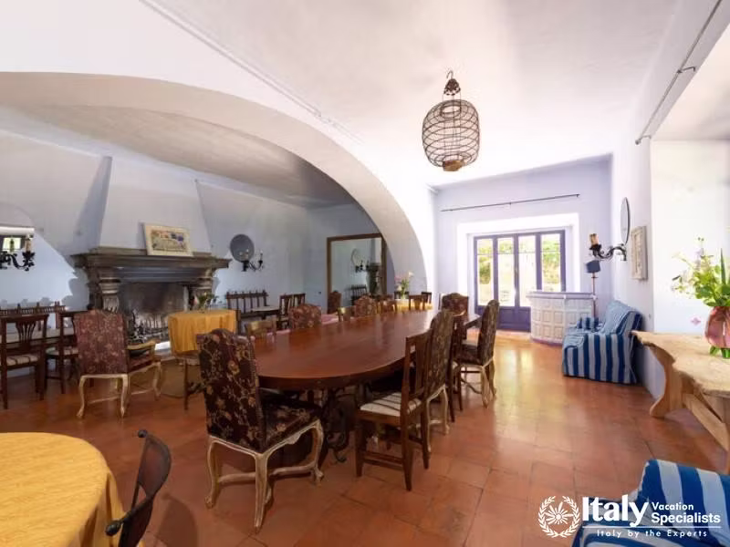 A large dining area with a long wooden table, numerous chairs, and a rustic, yet elegant design.