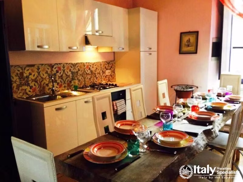 A modern kitchen with a colorful backsplash, dining table set for a meal, and contemporary furnishin
