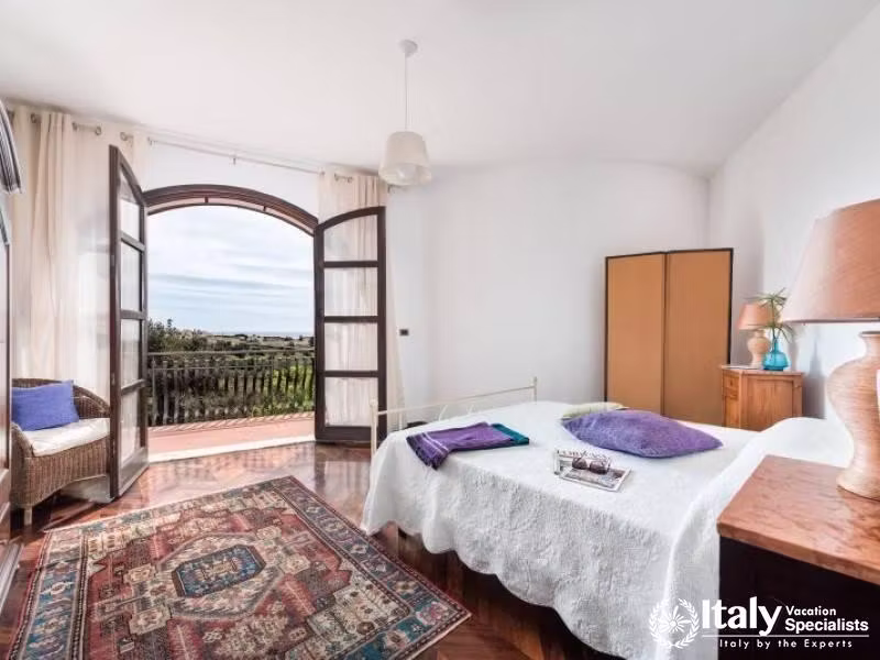 Bright bedroom with a balcony offering scenic views of the landscape.