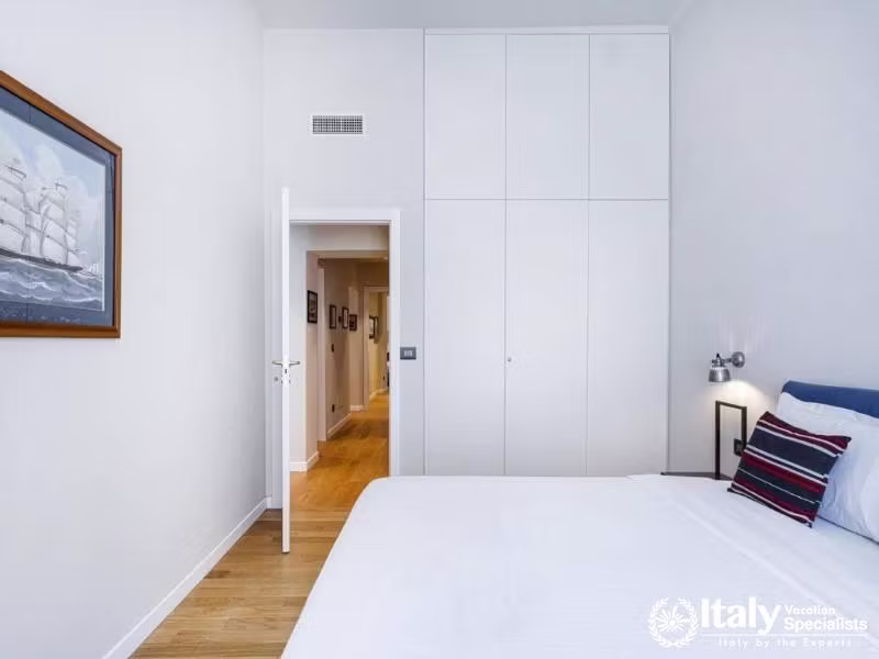 Minimalist bedroom with built-in storage and nautical artwork.