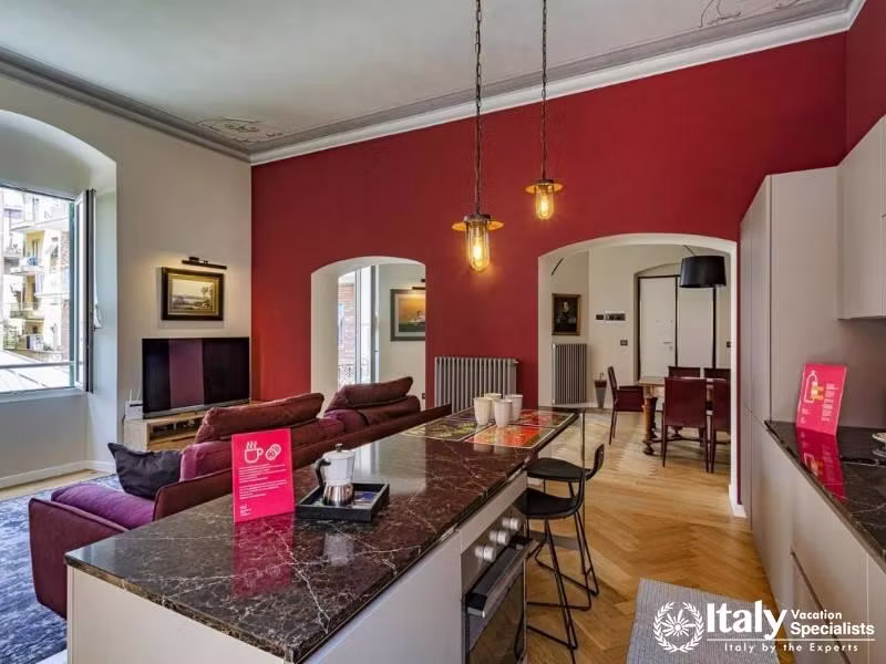 Stylish living area with red accent wall and open kitchen layout.