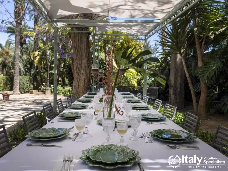 Villa Sole di Marsala features an exquisite outdoor dining space surrounded by lush greenery