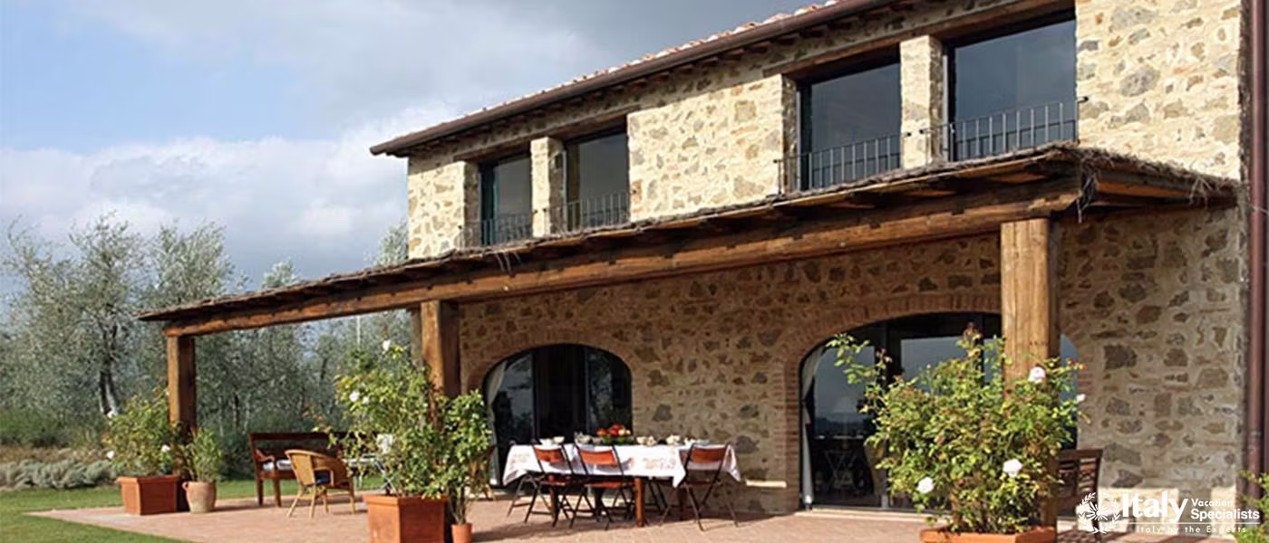 Stone villa with a covered patio and outdoor dining setup.