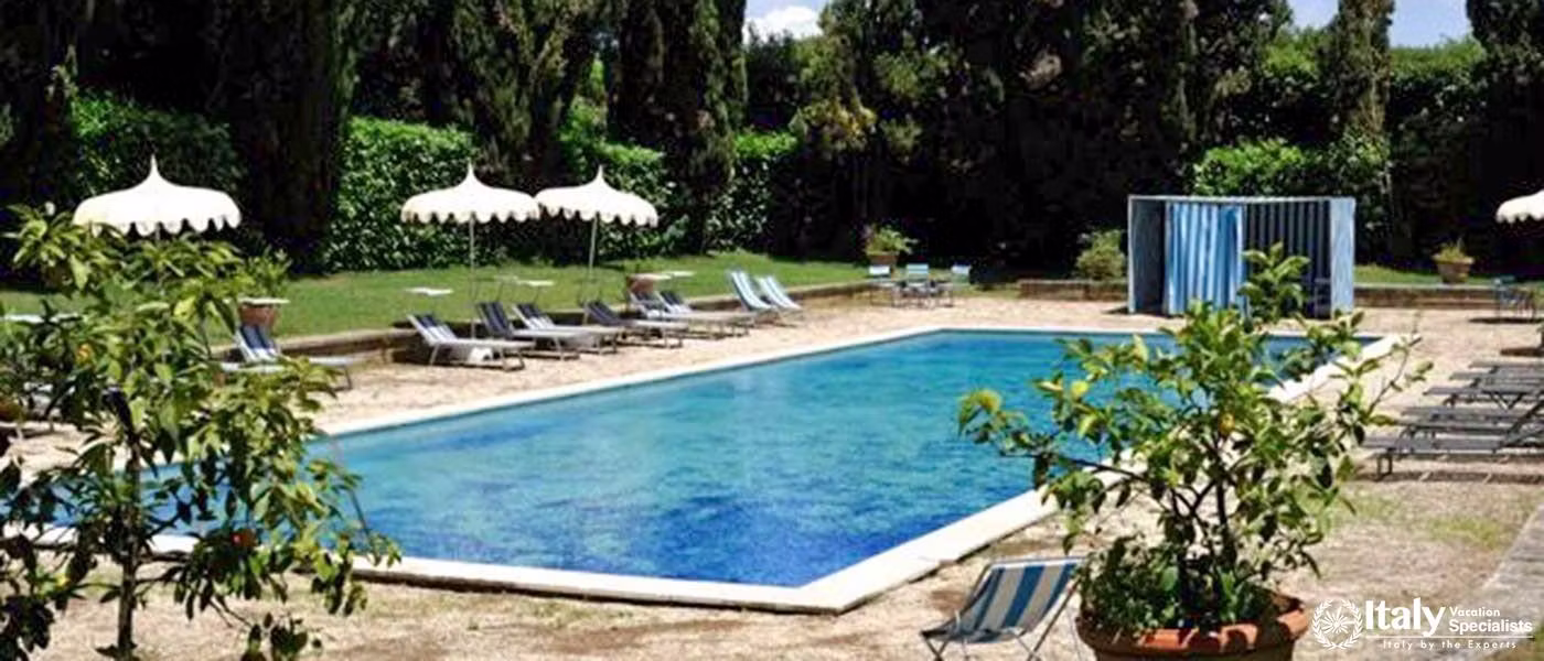 A large swimming pool surrounded by ancient chestnut trees.