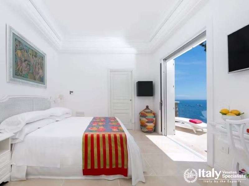 Bright bedroom with a colorful bed runner and ocean view.