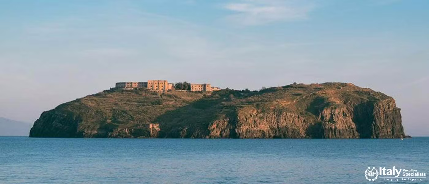 A view of the island of Ventotene, showcasing its rugged terrain and historic buildings atop the cli