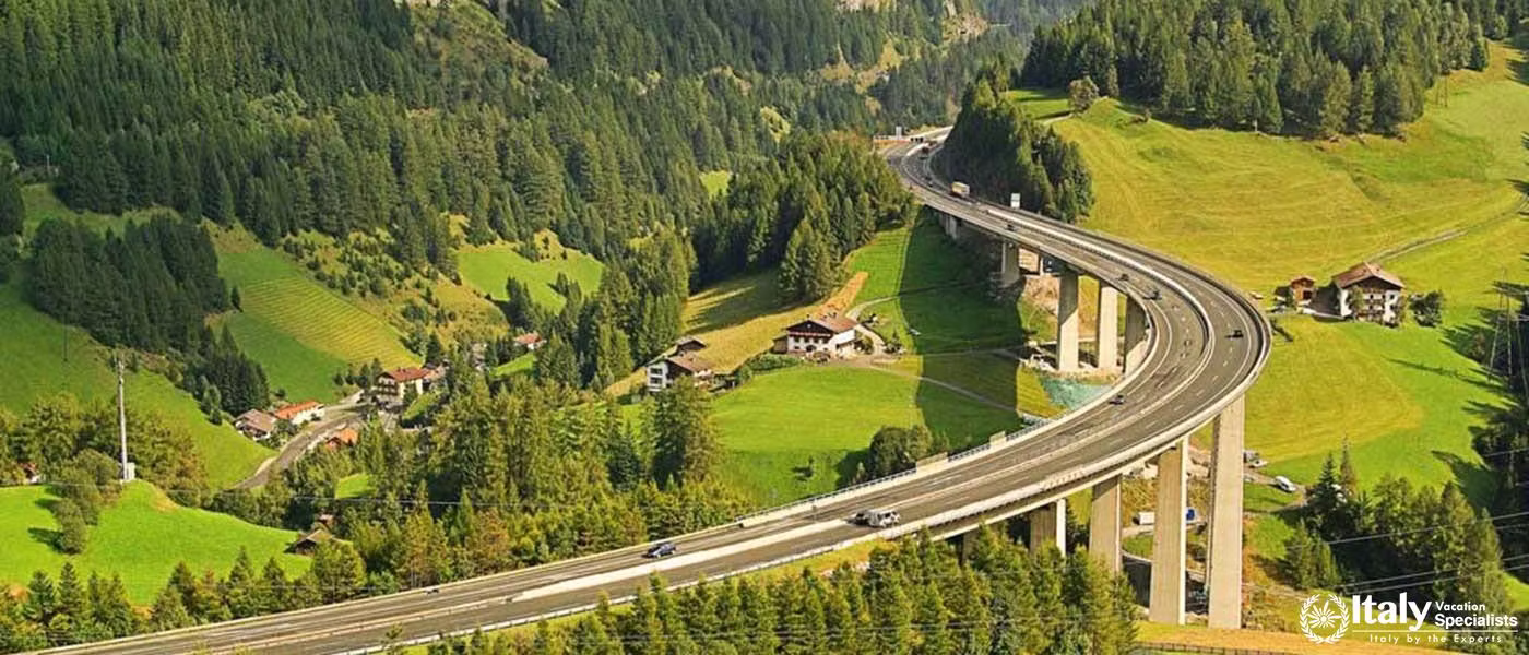 A scenic highway through a lush green valley with alpine houses.