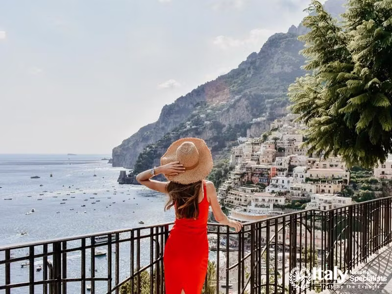 Fashion outdoor photo of beautiful woman with long dark hair in elegant dress and straw hat travelin