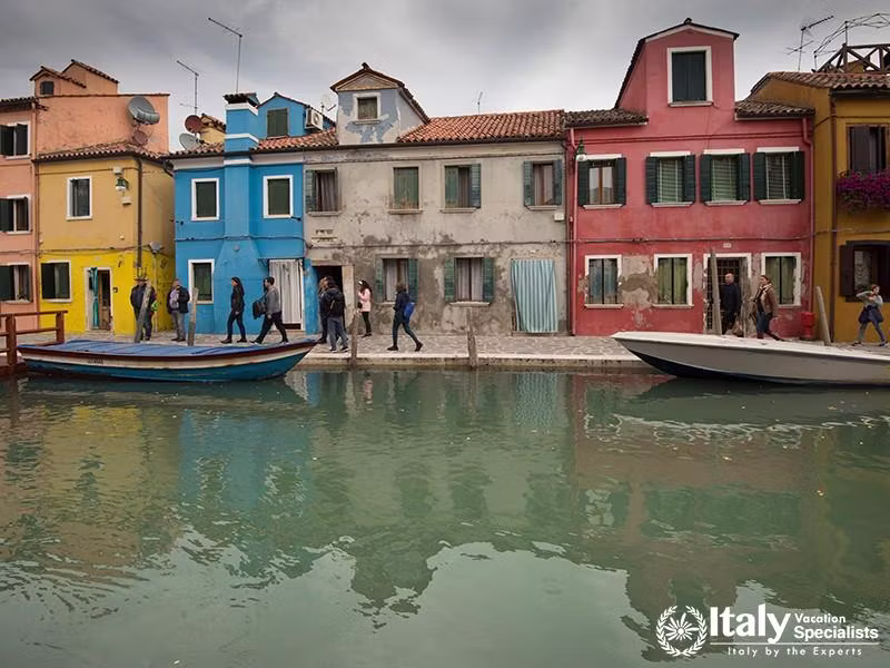 Burano, Italy, 27.10.2018 view of colourful houses and people walking on street of Burano with canal