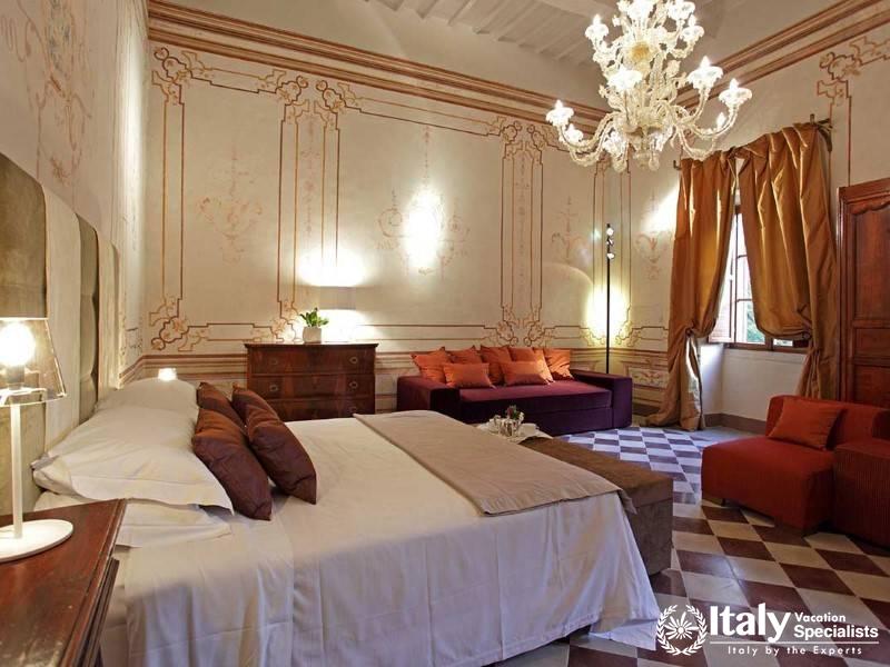 Elegant bedroom with ornate frescoes and a lavish chandelier, creating a regal atmosphere.