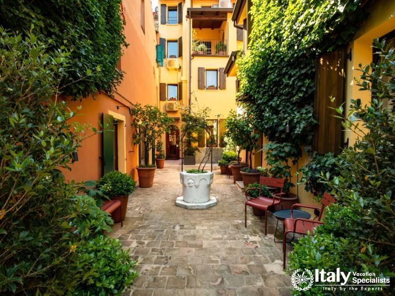 A quaint courtyard with a classic European feel, featuring vibrant ivy-covered walls.