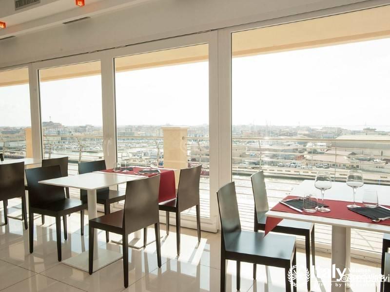 A bright and modern dining area with large windows overlooking a busy harbor.