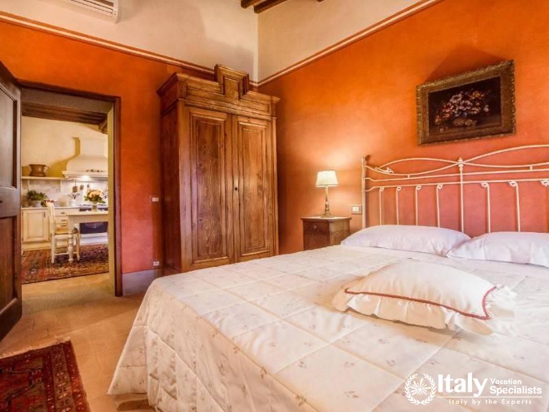 A spacious bedroom with rustic wooden furnishings, seamlessly connected to a traditional kitchen.